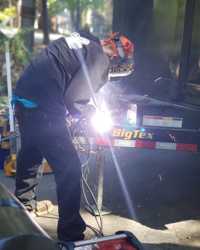 man welding a trailer hitch